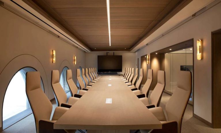 Meeting room in The Clift Royal Sonesta, featuring long table with seating for over a dozen attendees, cozy atmosphere, and large, wall-mounted TV.