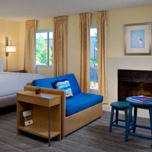 Sonesta ES Suites Flagstaff double bed guest room, featuring sofa, stool, coffee table, and fireplace.