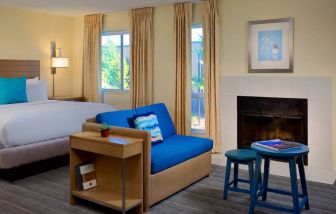 Sonesta ES Suites Flagstaff double bed guest room, featuring sofa, stool, coffee table, and fireplace.