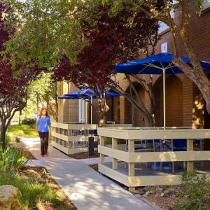 The hotel’s exterior has numerous trees and shaded table and chairs where guest can relax or co-work.