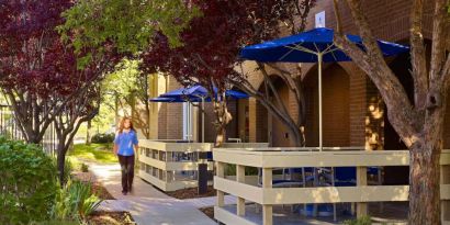 The hotel’s exterior has numerous trees and shaded table and chairs where guest can relax or co-work.