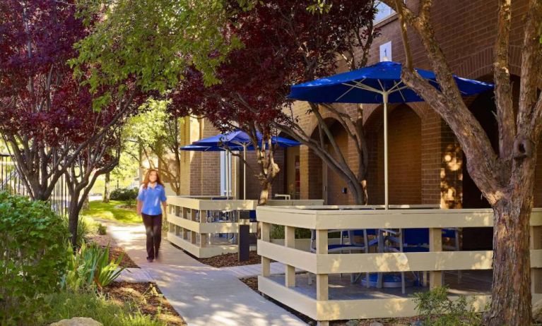 The hotel’s exterior has numerous trees and shaded table and chairs where guest can relax or co-work.