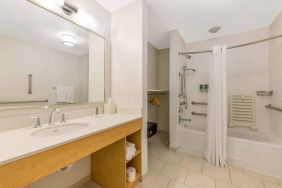 Guest bathroom in Sonesta ES Suites Charlotte Arrowood, furnished with large mirror, sink, bath and shower.