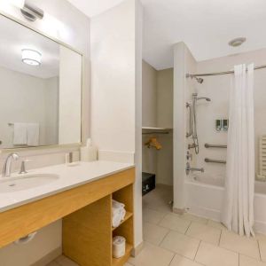 Guest bathroom in Sonesta ES Suites Charlotte Arrowood, furnished with large mirror, sink, bath and shower.