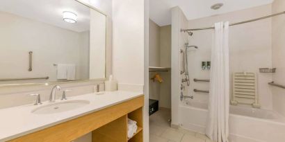 Guest bathroom in Sonesta ES Suites Charlotte Arrowood, furnished with large mirror, sink, bath and shower.