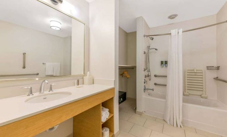 Guest bathroom in Sonesta ES Suites Charlotte Arrowood, furnished with large mirror, sink, bath and shower.