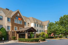 The hotel’s exterior has a pleasant abundance of greenery, including numerous trees, a covered entrance, and parking spaces.