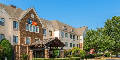 The hotel’s exterior has a pleasant abundance of greenery, including numerous trees, a covered entrance, and parking spaces.