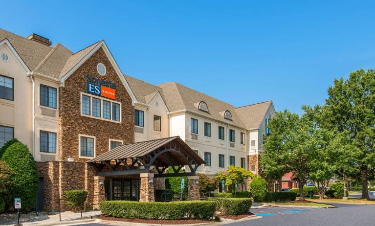 The hotel’s exterior has a pleasant abundance of greenery, including numerous trees, a covered entrance, and parking spaces.