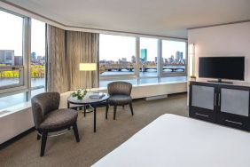 Royal Sonesta Boston double bed guest room, featuring wonderful city views, a widescreen TV, two chairs, and a coffee table.