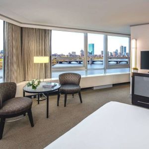 Royal Sonesta Boston double bed guest room, featuring wonderful city views, a widescreen TV, two chairs, and a coffee table.