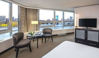 Royal Sonesta Boston double bed guest room, featuring wonderful city views, a widescreen TV, two chairs, and a coffee table.