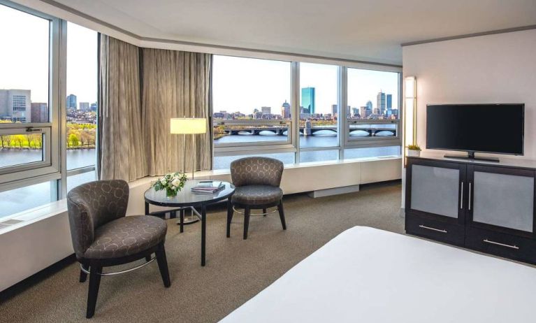 Royal Sonesta Boston double bed guest room, featuring wonderful city views, a widescreen TV, two chairs, and a coffee table.