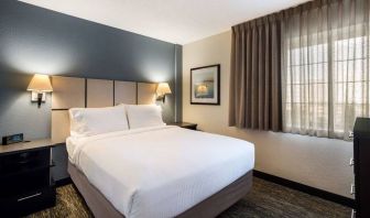 Sonesta Simply Suites Chicago Waukegan double bed guest room, featuring bedside lamps, art on the wall, and window.