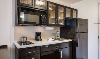 Sonesta Simply Suites Chicago Waukegan guest room kitchen, including sink, microwave, oven and hob, and fridge-freezer.