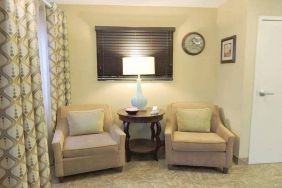 Sonesta Simply Suites Chicago Waukegan’s lobby is furnished with two armchairs, a coffee table, and a window.