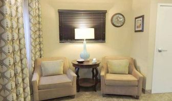 Sonesta Simply Suites Chicago Waukegan’s lobby is furnished with two armchairs, a coffee table, and a window.