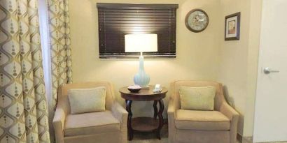 Sonesta Simply Suites Chicago Waukegan’s lobby is furnished with two armchairs, a coffee table, and a window.