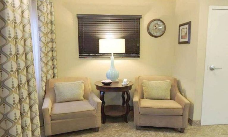 Sonesta Simply Suites Chicago Waukegan’s lobby is furnished with two armchairs, a coffee table, and a window.