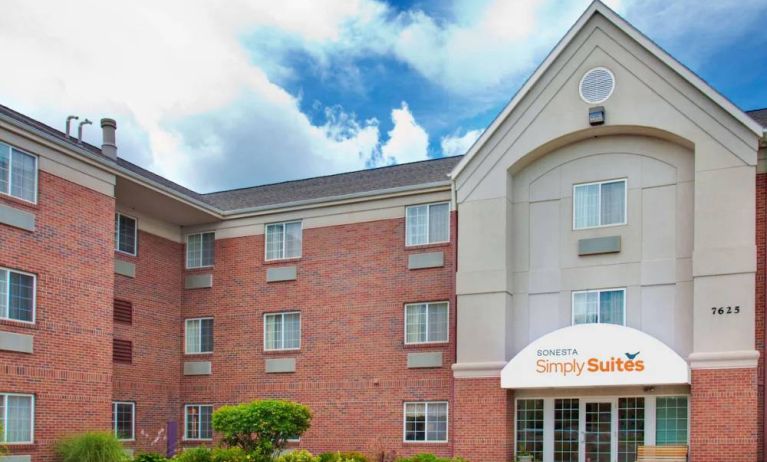 Sonesta Simply Suites Des Moines’ exterior has pleasant greenery, parking, and red brick architecture.