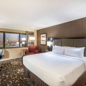 Double bed guest room in Sonesta Los Angeles Airport LAX, including armchair, desk and chair, and window.