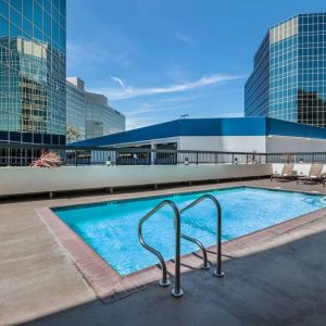 Sonesta Los Angeles Airport LAX’s outdoor pool has loungers by the side and towering buildings nearby.