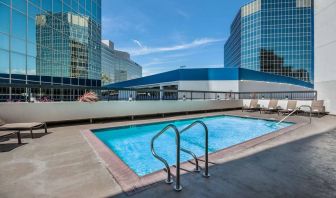 Sonesta Los Angeles Airport LAX’s outdoor pool has loungers by the side and towering buildings nearby.