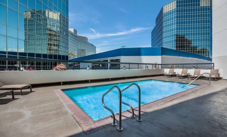 Sonesta Los Angeles Airport LAX’s outdoor pool has loungers by the side and towering buildings nearby.