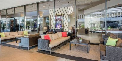 Sonesta Los Angeles Airport LAX’s lobby lounge features comfy sofa and armchair seating, and large coffee tables.