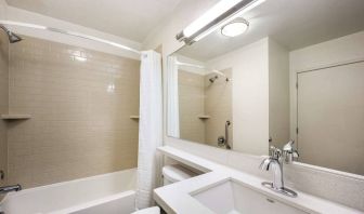 Guest bathroom in Sonesta Simply Suites Dallas Galleria, featuring shower and bath, mirror and sink, and a lavatory.