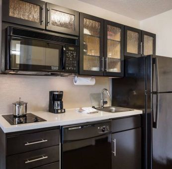 Sonesta Simply Suites Dallas Galleria guest room kitchen, furnished with fridge-freezer, hob, oven, and microwave.