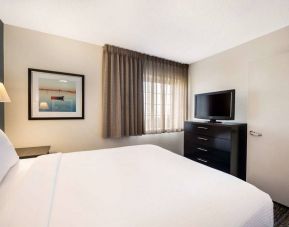 Double bed guest room in Sonesta Simply Suites Dallas Galleria, with art on the wall, window, and television.