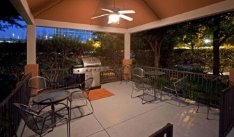 Sonesta Simply Suites Dallas Galleria’s barbecue area features tables and chairs under cover, with barbecue facilities and nearby trees.