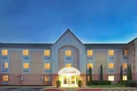 Sonesta Simply Suites Dallas Galleria’s exterior has well-kept greenery, including potted plants, clear signage, and parking spaces.