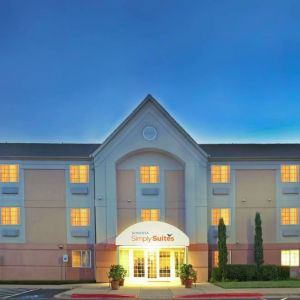 Sonesta Simply Suites Dallas Galleria’s exterior has well-kept greenery, including potted plants, clear signage, and parking spaces.