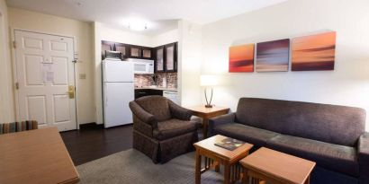 Lounge area in Sonesta ES Suites Austin The Domain Area guest room, furnished with sofa, armchair, and coffee tables.