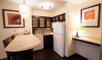 Sonesta ES Suites Austin The Domain Area guest room kitchen, including fridge-freezer, microwave, and breakfast bar with two stools.