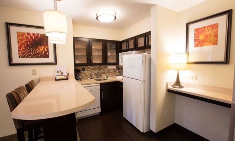 Sonesta ES Suites Austin The Domain Area guest room kitchen, including fridge-freezer, microwave, and breakfast bar with two stools.