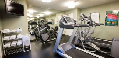 The fitness center at Sonesta ES Suites Austin The Domain Area includes a widescreen television, plenty of towels, and multiple exercise machines.