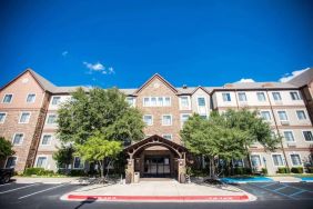 The hotel’s exterior has a covered entranceway flanked by trees, in addition to numerous parking spaces.