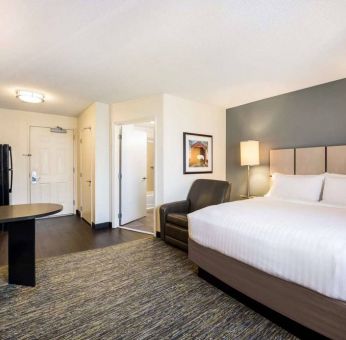 Sonesta Simply Suites Pittsburgh Airport double bed guest room, including armchair and a kitchen area.