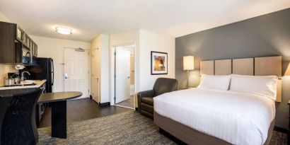 Sonesta Simply Suites Pittsburgh Airport double bed guest room, including armchair and a kitchen area.