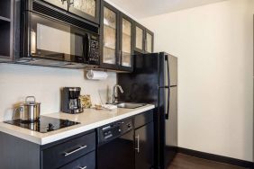 Fully equipped guest room kitchen in Sonesta Simply Suites Pittsburgh Airport, with fridge-freezer, microwave, oven, hob, and sink.