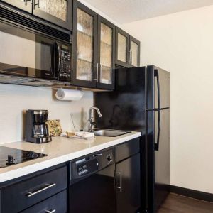 Fully equipped guest room kitchen in Sonesta Simply Suites Pittsburgh Airport, with fridge-freezer, microwave, oven, hob, and sink.