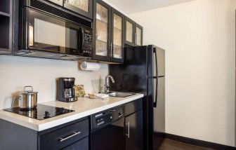 Fully equipped guest room kitchen in Sonesta Simply Suites Pittsburgh Airport, with fridge-freezer, microwave, oven, hob, and sink.