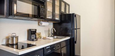 Fully equipped guest room kitchen in Sonesta Simply Suites Pittsburgh Airport, with fridge-freezer, microwave, oven, hob, and sink.