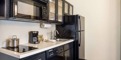 Fully equipped guest room kitchen in Sonesta Simply Suites Pittsburgh Airport, with fridge-freezer, microwave, oven, hob, and sink.