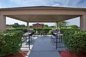 Sonesta Simply Suites Pittsburgh Airport’s gazebo features seating and tables outdoors and under cover, with two barbecues and a surrounding hedge.