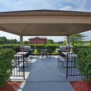 Sonesta Simply Suites Pittsburgh Airport’s gazebo features seating and tables outdoors and under cover, with two barbecues and a surrounding hedge.