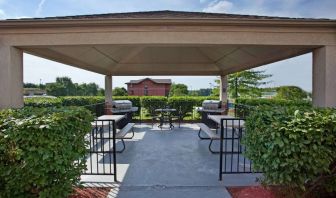 Sonesta Simply Suites Pittsburgh Airport’s gazebo features seating and tables outdoors and under cover, with two barbecues and a surrounding hedge.